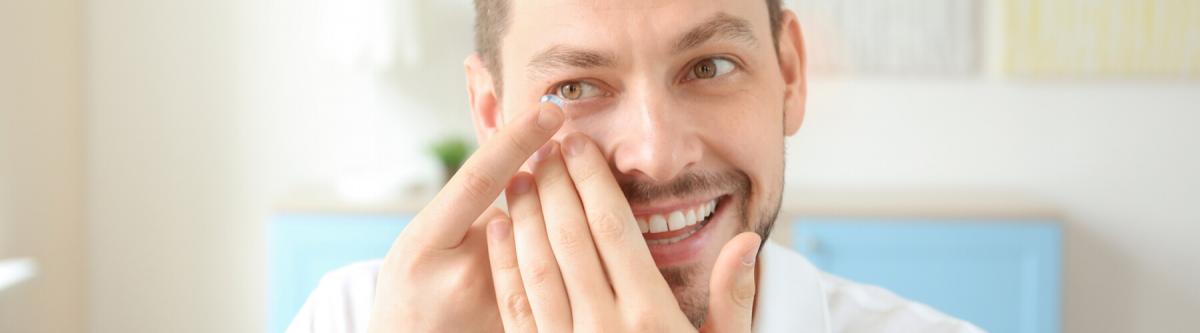 young adult man putting in contact lenses