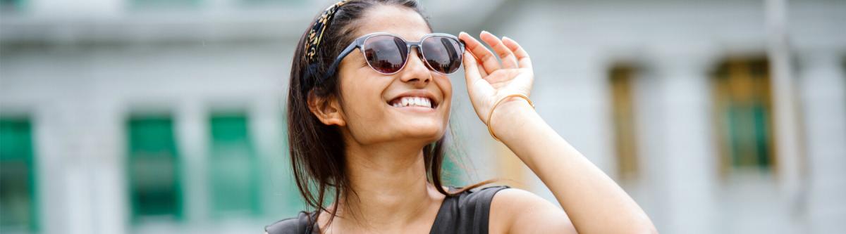 portrait of a young indian tourist looking up, wearing sunglasses, or protective eyewear