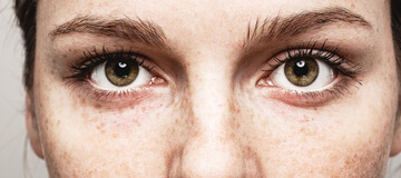 close up of the eyes of a young woman with freckles
