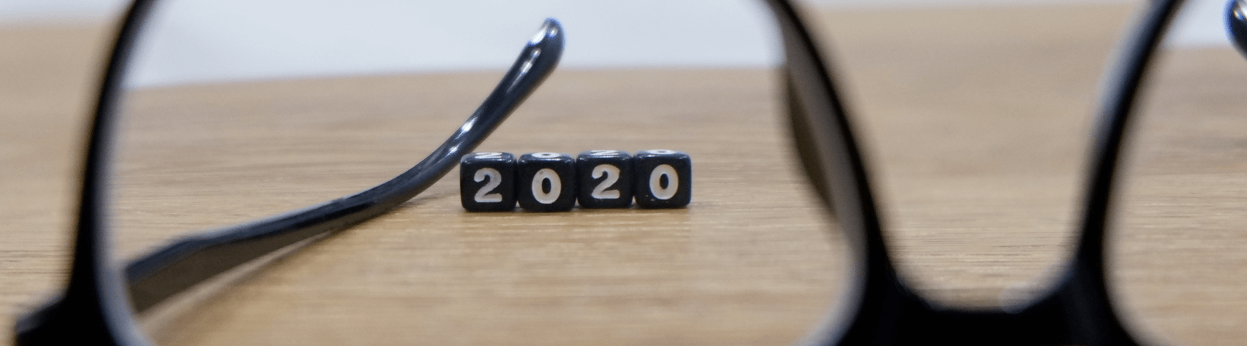Glasses on wooden table with selective focus on cubes that read 2020