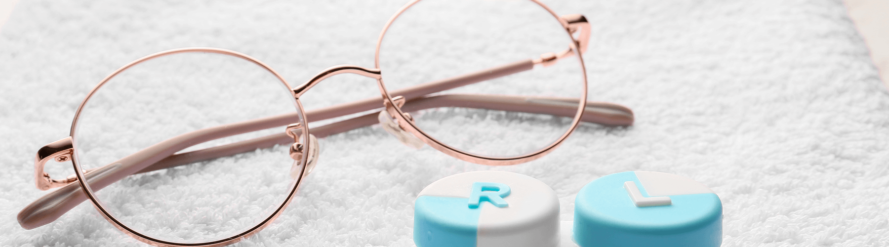 Container with contact lenses and glasses on towel