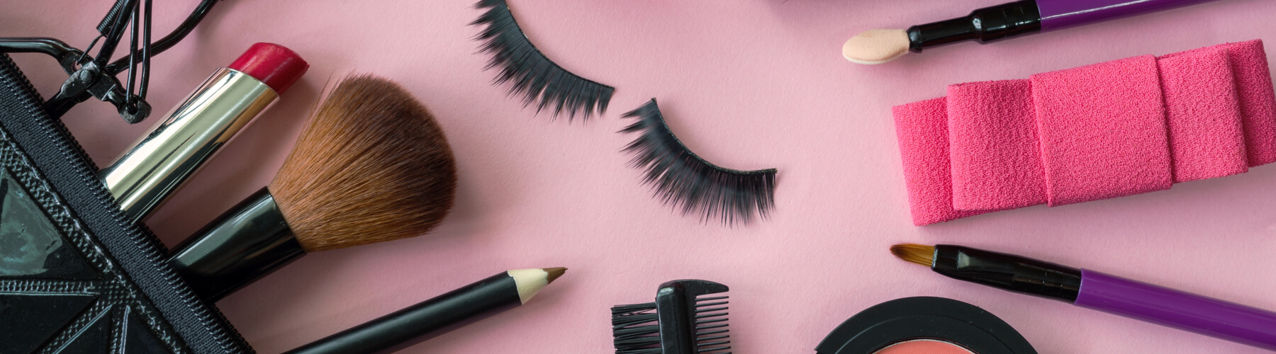 various makeup products and cosmetics isolated on pink background