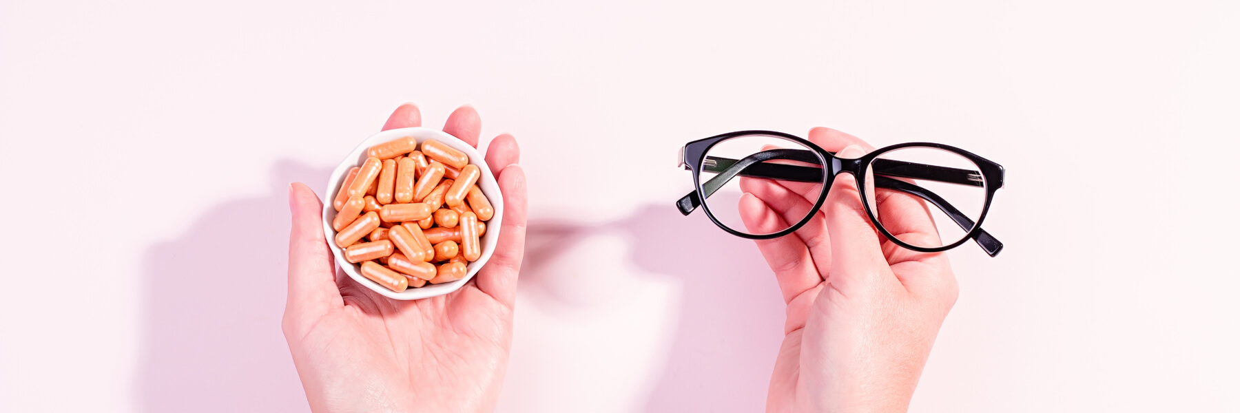 holding glasses in one hand and vitamins in the other hand