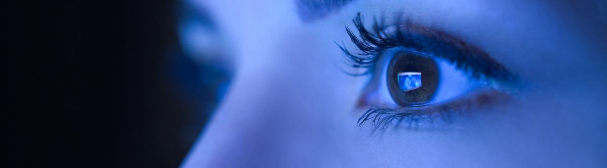 Close-up of beautiful young woman eyes looking at monitor, working with computer, laptop. Monitor blue light is reflected in her eyes.