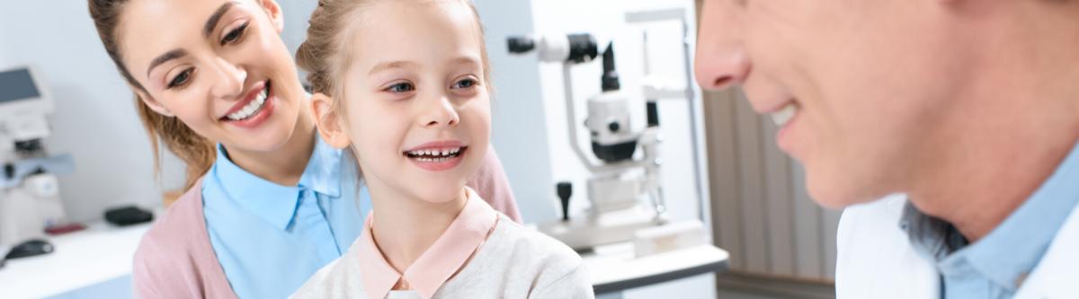 mother and daughter visiting eye doctor, and choosing eye or contact lenses in clinic