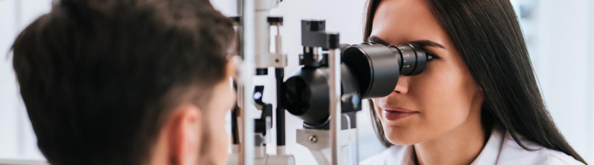 Female optometrist doing an eye exam on young male patient