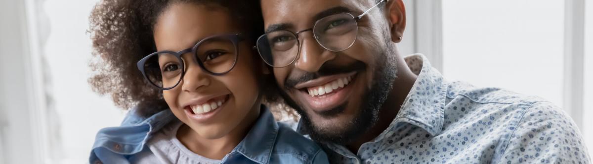 young african american girl and her dad wearing glasses smiling, closeup