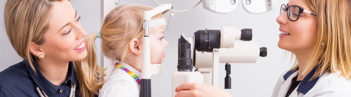 mom and daughter getting an eye exam from an optometrist