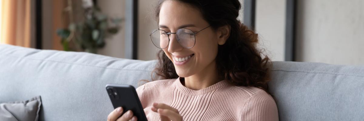 woman in glasses smiling at phone screen