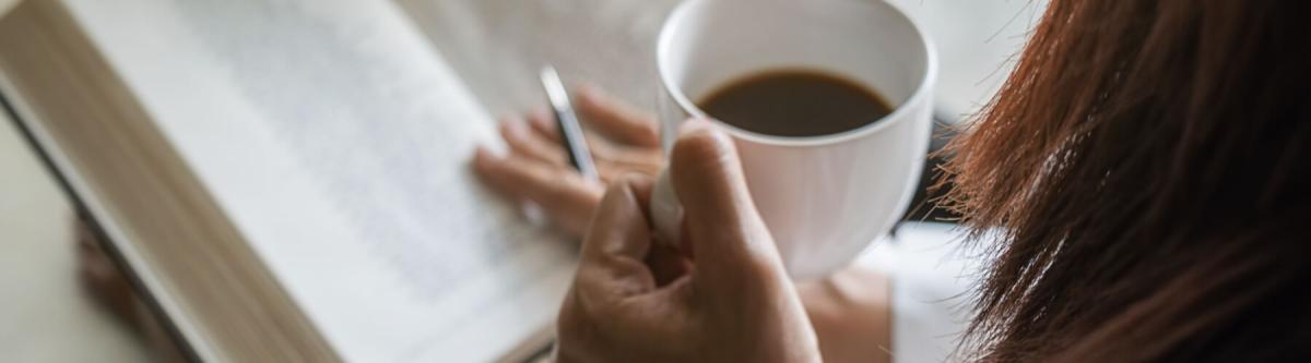 woman holding coffee and reading by a window