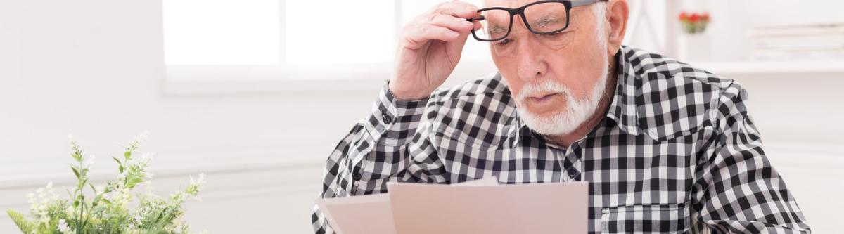 Senior man struggling to read documents with current glasses or lenses