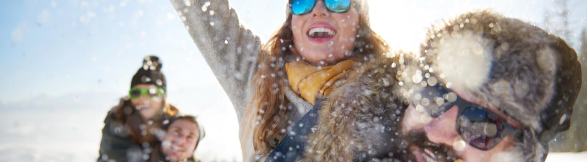 group of friends playing in the snow, all wearing sunglasses in winter